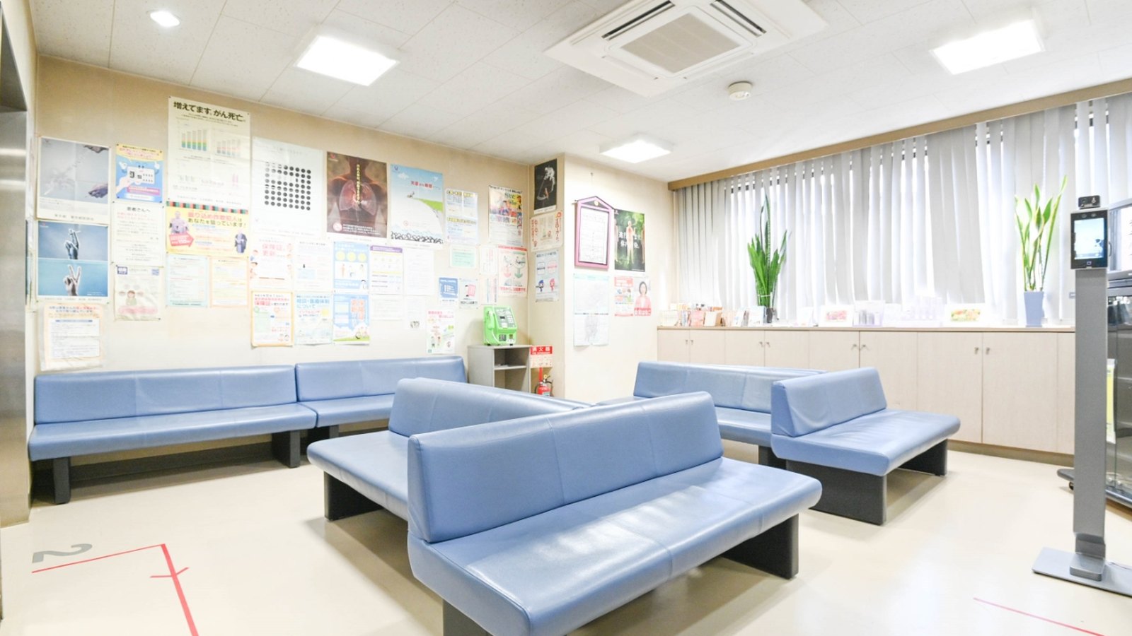 魚住総合クリニックの待合室。青い長椅子が並び、窓から自然光が入っている