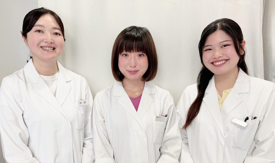 白衣を着た事務スタッフ3名が並んで立っている